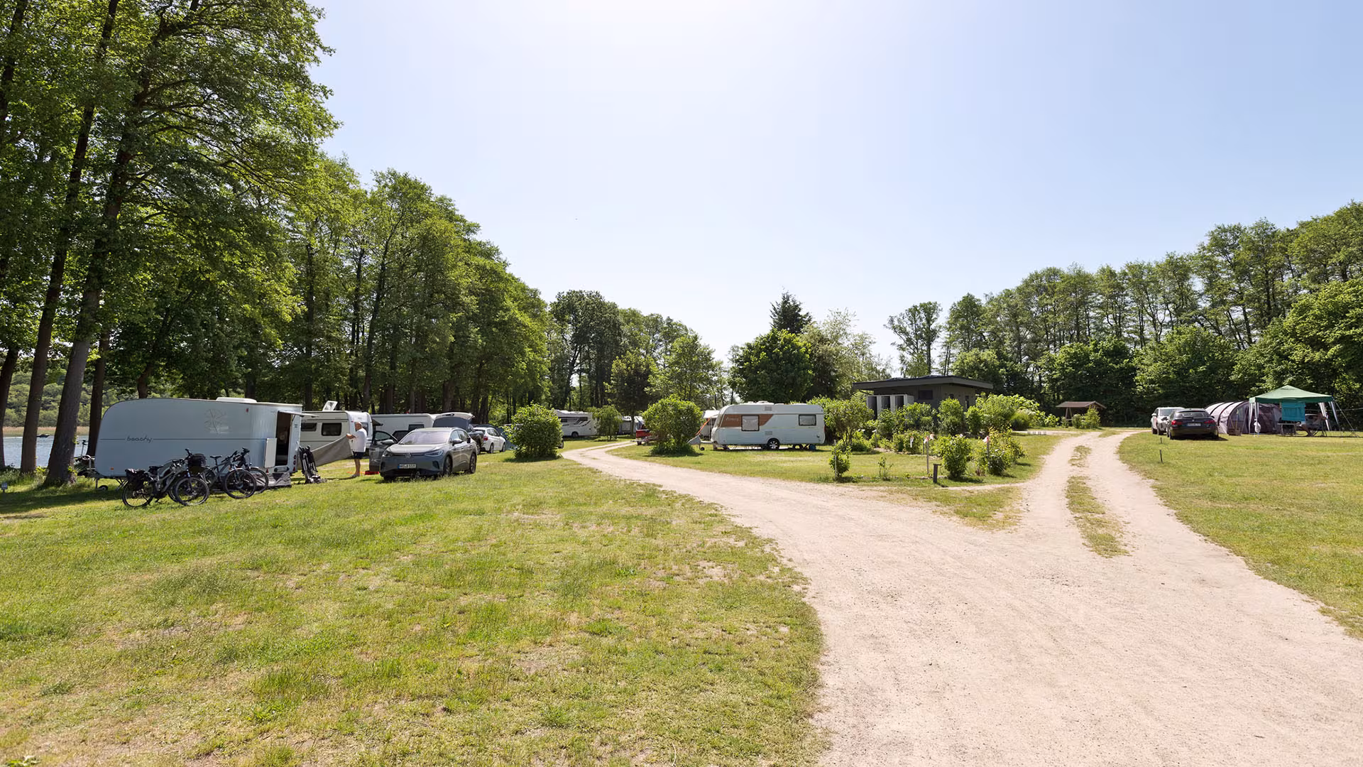 Cesta přírodním kempem s karavany a stromy